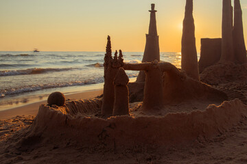 Sand Castle on Beach. Built House sand castle with towers on the south shore of the sandy beach blue sea. Castle of sand on the beach by the sea. Sand castle by sea on summer © Alex J