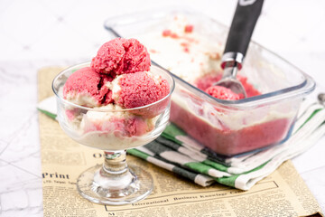 Strawberry frozen yogurt in glass bowl, ice cream balls, container with homemade sundae