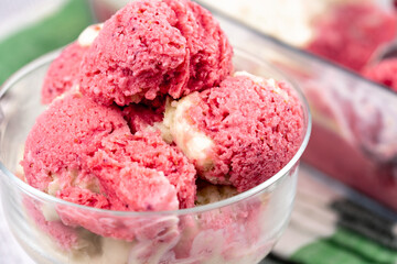 Strawberry frozen yogurt in glass bowl, ice cream balls, container with homemade sundae