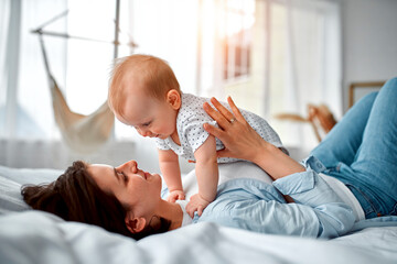 Loving mom carying of her newborn baby at home.Mom and baby boy playing in sunny bedroom. Parent...