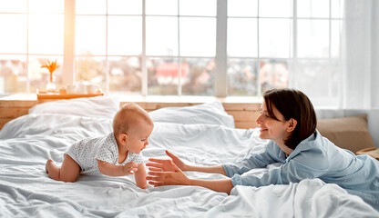 Loving mom carying of her newborn baby at home.Mom and baby boy playing in sunny bedroom. Parent...