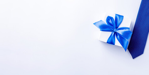 Fathers gift. White box with bow ribbon, blue bowtie or tie on light background. Concept of Fathers Day greeting card, copy space for text.