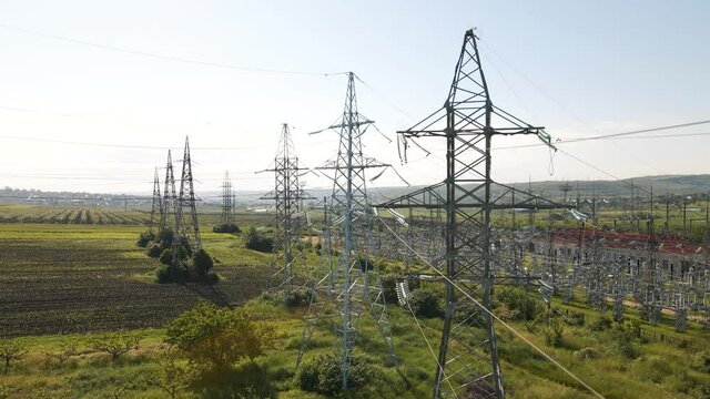 Aerial cinematic clip drone flies rising over a wheat field and High voltage electric towers. Drone flies over a green agricultural wheat field