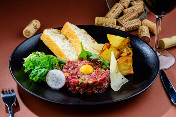 Raw tasty beef tartare with egg yolk and toasts on the plate in a cafe