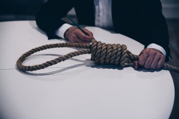 Young man preparing to commit suicide by hanging. Farewell letter