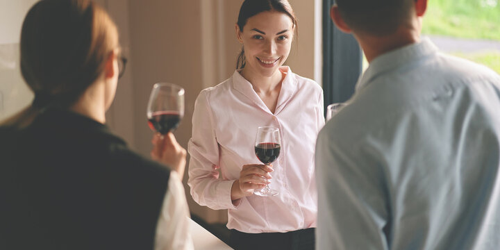 Front view of successful business woman smiling and holding red wine