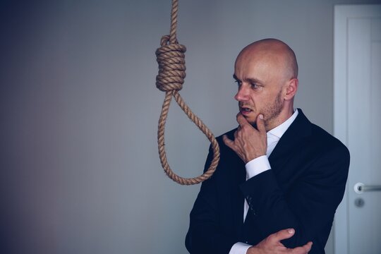 A businessman in a suit contemplates committing suicide. Final decision.