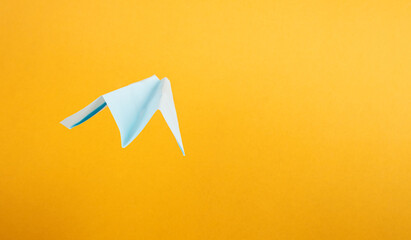 summer tourism, origami paper airplane on yellow background with copy space.
