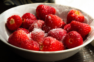 a plate of strawberries with sugar close up