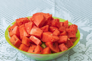 Close up macro view of bowl with cut red watermelon isolated on white cloth background.