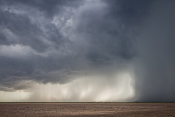 A severe storm with an intense precipitation shaft dumps rain and hail over the flat landscape of...