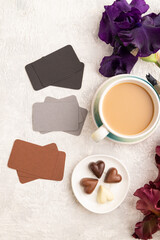 Set of gray, black, brown business cards with cup of cioffee, chocolate candies, iris flowers on gray concrete background. top view, flat lay, copy space.