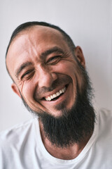 Fototapeta premium Happy muslim man with beard dressed in white t-shirt is laughing. human emotions. Looking at camera