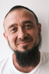 Happy muslim man with beard dressed in white t-shirt is smiling. human emotions. Looking at camera