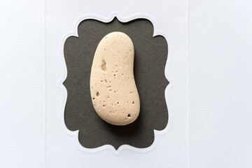 ear shaped stone inside a fancy white paper frame with space for text