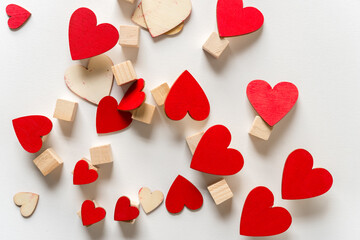 tumbling hand painted red hearts and untreated wood craft cubes on a light background