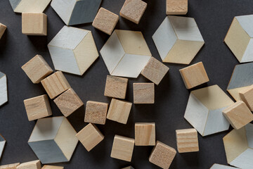 untreated wood craft cubes and painted trompe l'oeil (hexagonal) cubes on dark gray background