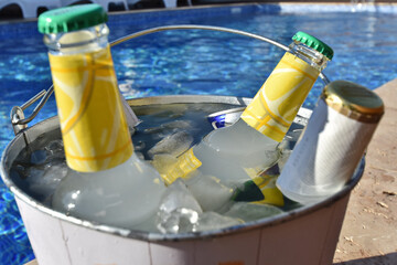 Closeup of cold drinks in a bucket full of ice near the pool