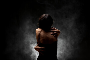 half silhouette modern ballet dancer posing on dark background with smoke