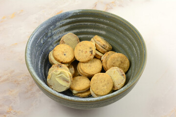 Small blueberry cereal cookies covered in white chocolate on one side in snack bowl on table