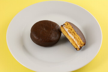 Banana marshmallow chocolate pie cookie on white snack plate on yellow background