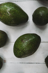 Whole and halved avocado on wooden table