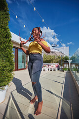 young african american woman having fun, relaxing on rooftop patio at home