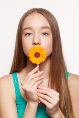 Teenager girl with  flower lollipop in hands closing mouth.