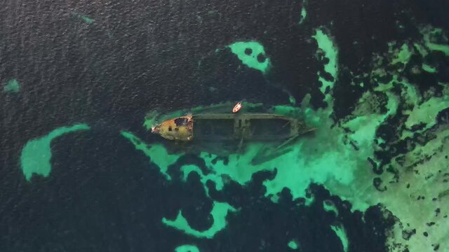 Sunken ship, shipwreck on shallow waters, reef and corals. Ascending top view. Croatia.