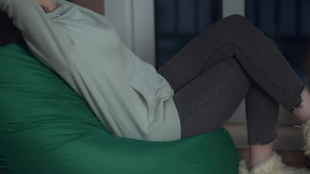 Girl in the evening in her room sits on a beanbag throwing her hands behind her head, concept relaxation
