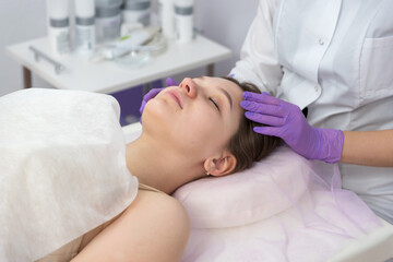 Cosmetologist preparing to doing cosmetic facial treatments for the young woman.