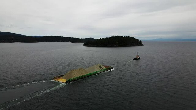 Aerial shot of tug boat pulling sand in British Columbia