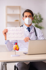 Young male doctor cardiologist working in the clinic during pand