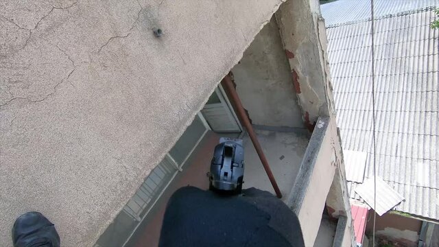 Special forces agent aiming a gun POV while hanging from a rope on the side of a building.