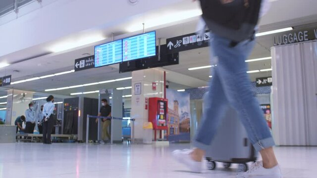 4K Asian tourist women wear protective fack mask with travel bag backpack checking timetable or schedule of flights in Airport COVID-19 Coronavirus pandemic. safe traveling and tourism