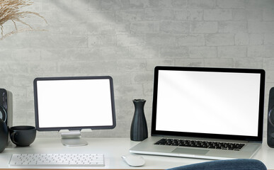 Mockup blank screen laptop and tablet on white table in modern studio room.