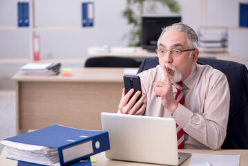 Old male employee sitting at workplace
