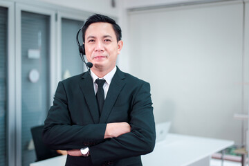 Portrait of call center asian man operator standing with headset looking to camera at office