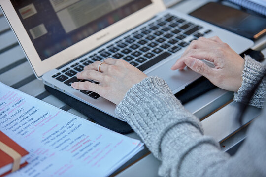 Young female student typing on her laptop outdoors
