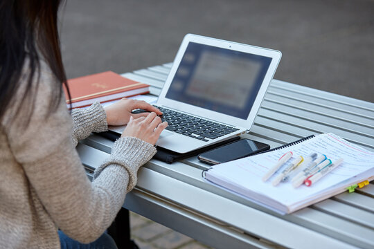 Young female student studying on her laptop outdoors
