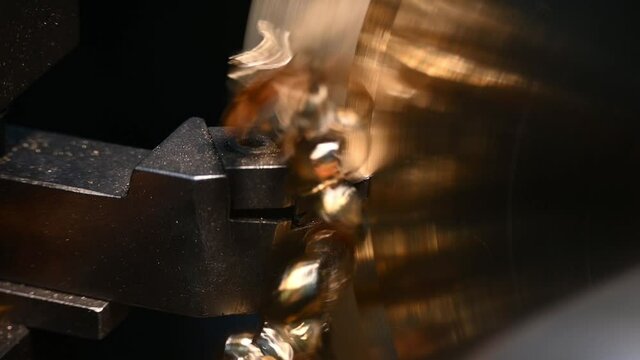 Close-up scene of lathe machine cutting the brass material part with unbroken snarls chip. The metal working process by turning machine.