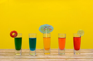 Bebidas coloridas sobre mesa de madera con fondo amarillo. Fondo de verano.