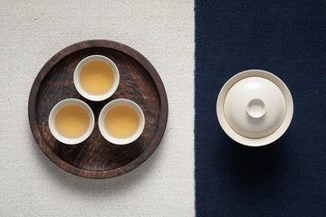 Obraz na płótnie Canvas Three cups of tea are placed in a round black walnut wooden tray. Tea art tea seats.