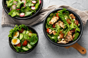 Freshly made salads on light gray background. Seasonal food concept.