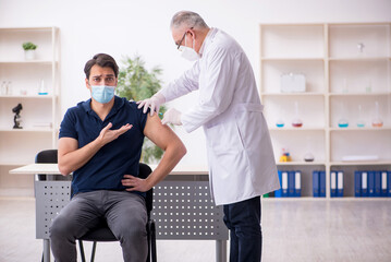 Young male patient visiting old male doctor in vaccination conce