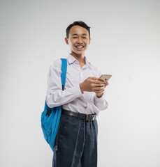 a boy wearing a junior high school uniform smiles while holding a cellphone from an isolated...