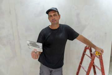 Male builder, master office, plasterer with a tool in working clothes