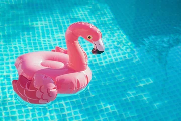 Gordijnen Inflatable pink flamingo in a pool with water. Summer Concept © murziknata
