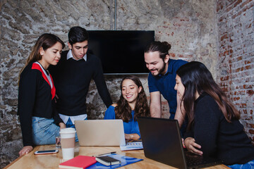 Young hispanic business team sharing new ideas using laptop at office desk in Mexico City