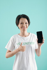 Pretty smiling young volunteers holding smartphone and showing thumbs-up